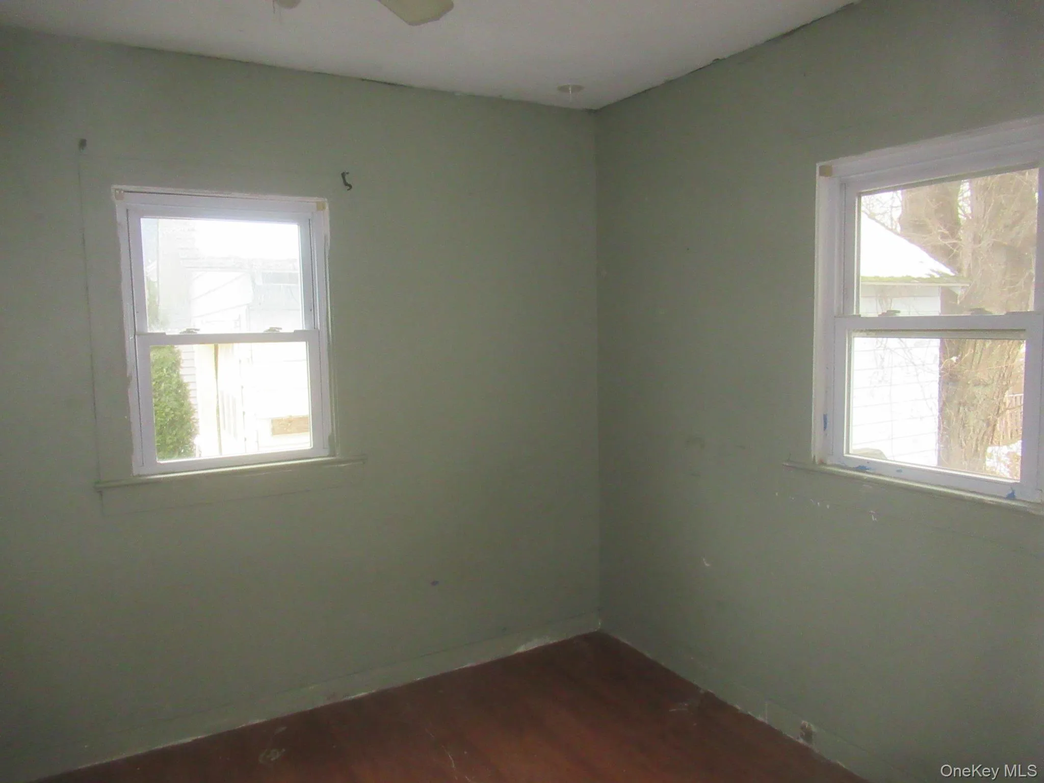 Unfurnished room with dark wood-style flooring, healthy amount of natural light, and ceiling fan Unfurnished room with dark wood-style flooring, healthy amount of natural light, and ceiling fan