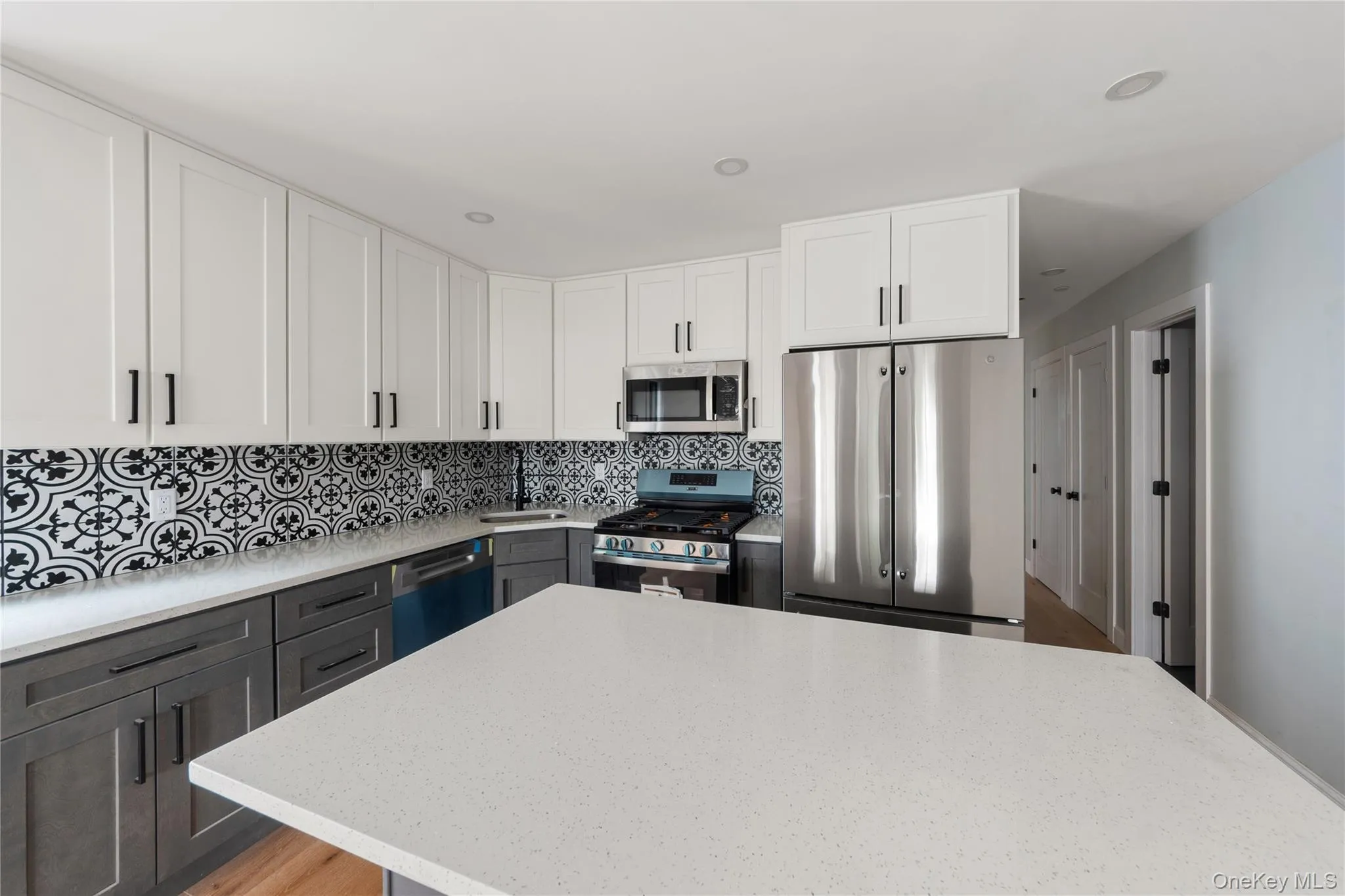 Kitchen with white cabinetry, stainless steel appliances, tasteful backsplash, light stone countertops, and recessed lighting Kitchen with white cabinetry, stainless steel appliances, tasteful backsplash, light stone countertops, and recessed lighting