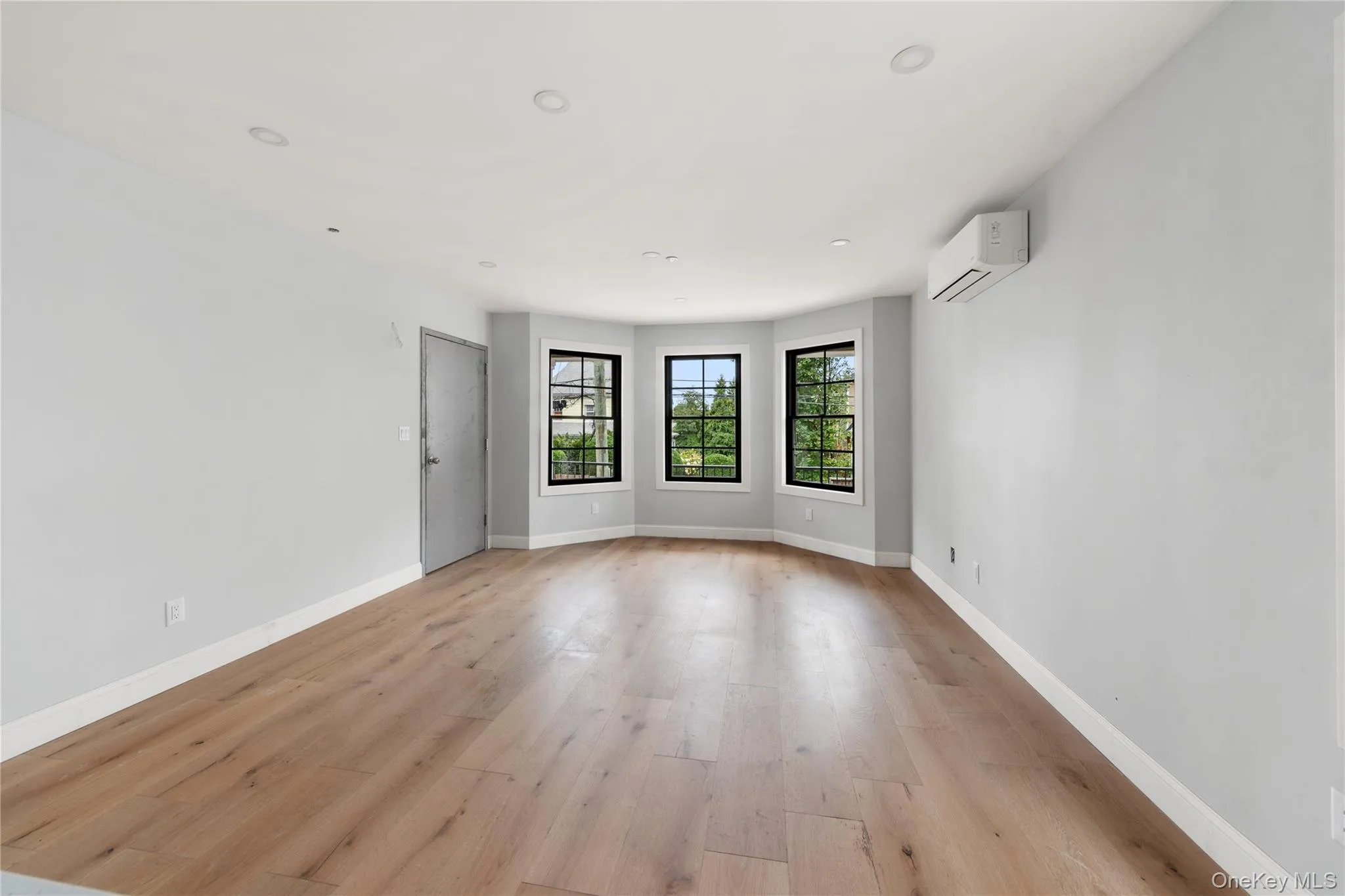 Empty room featuring light wood finished floors, recessed lighting, and an AC wall unit Empty room featuring light wood finished floors, recessed lighting, and an AC wall unit