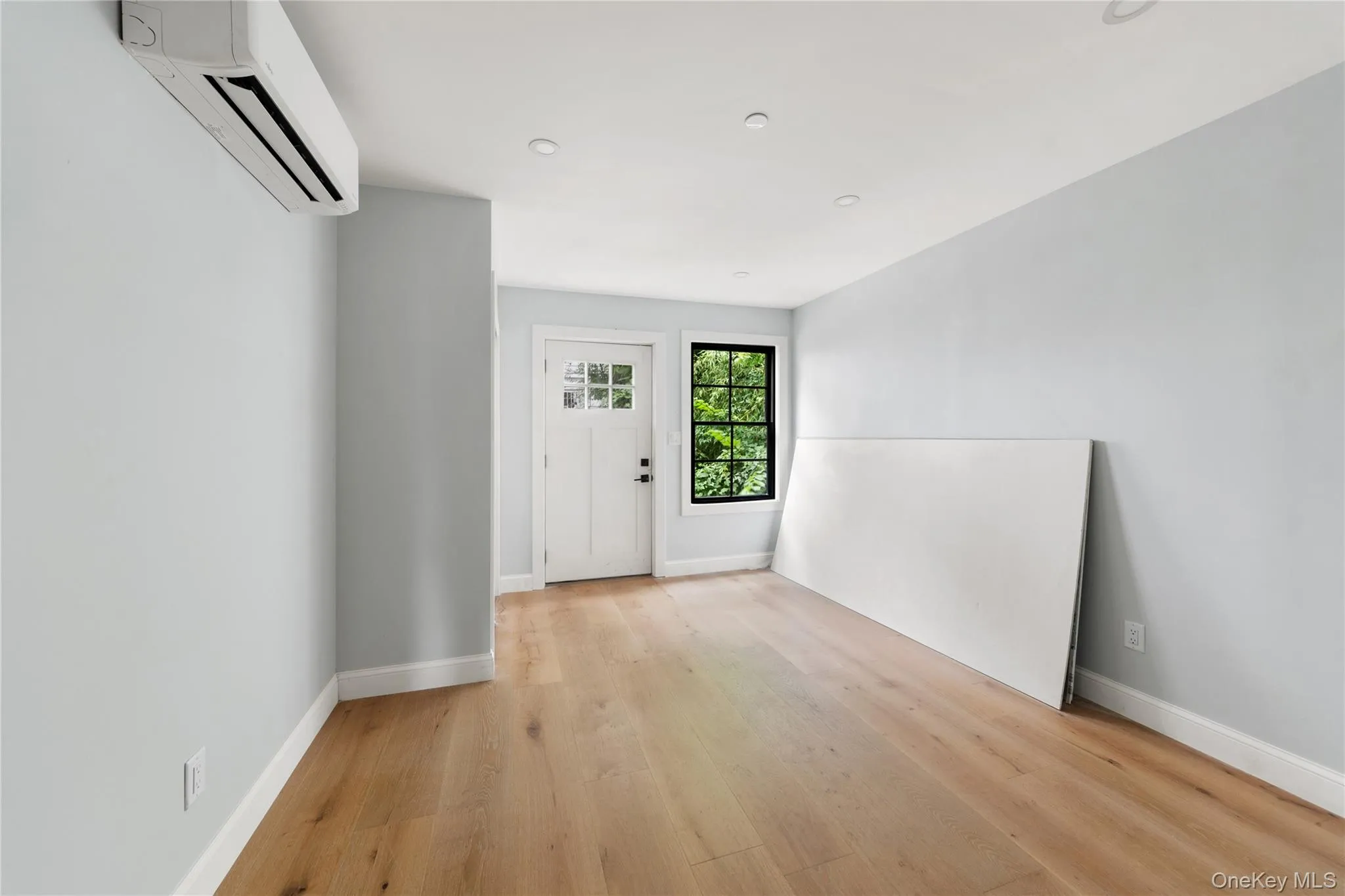 Foyer with light wood-type flooring and a wall mounted air conditioner Foyer with light wood-type flooring and a wall mounted air conditioner