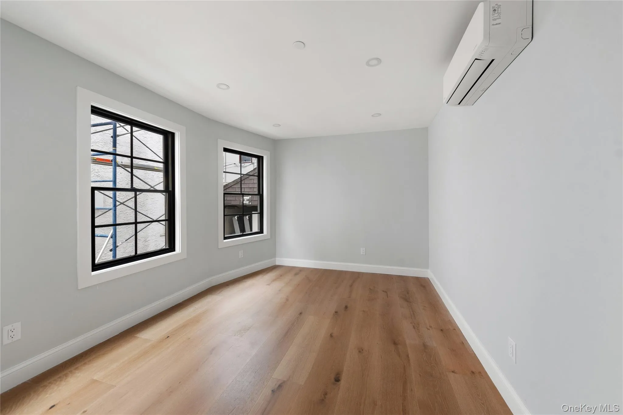Spare room with light wood finished floors, a wall mounted AC, and recessed lighting Spare room with light wood finished floors, a wall mounted AC, and recessed lighting