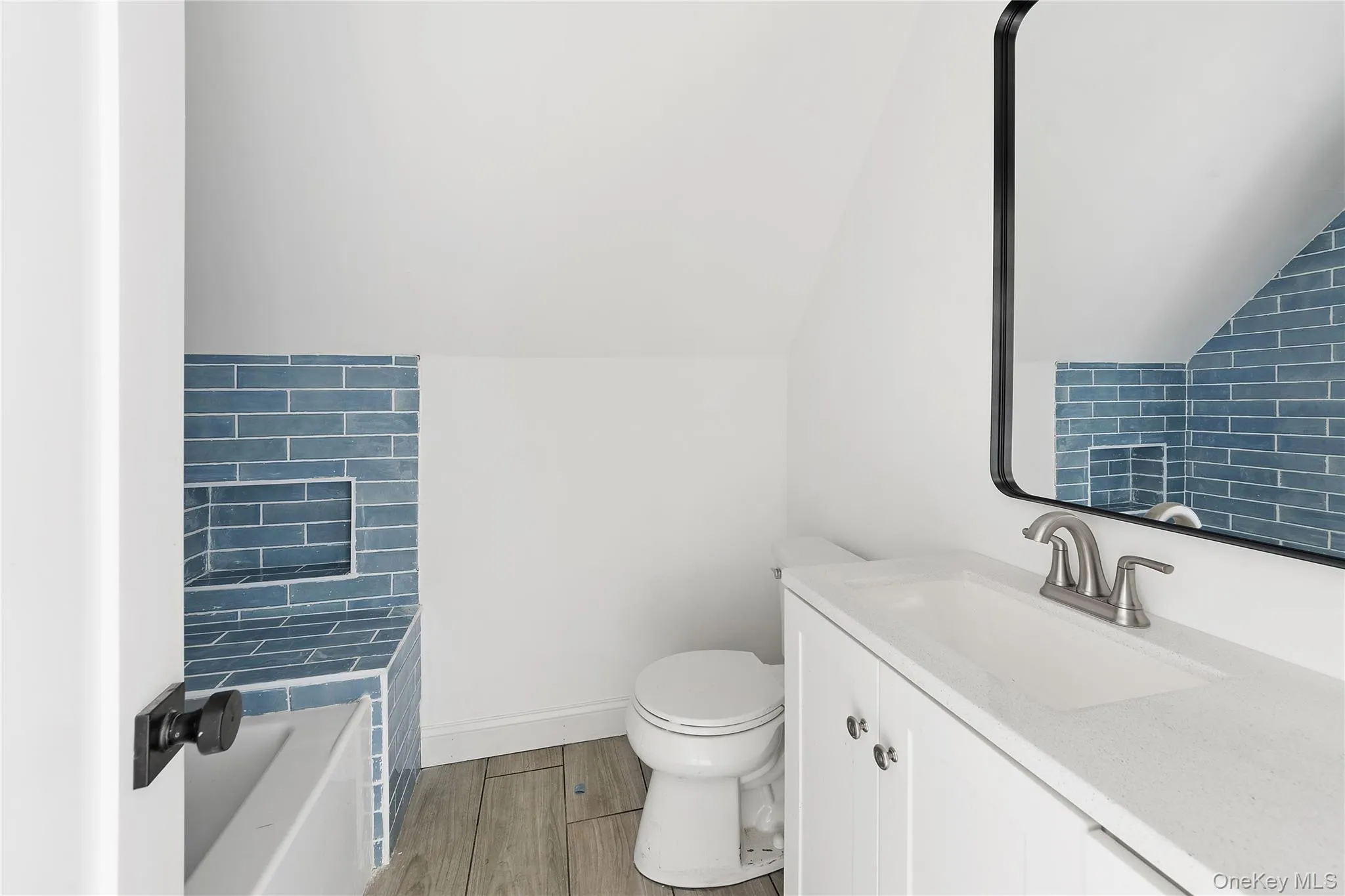 Full bath with vanity, wood tiled floors, a tub to relax in, and vaulted ceiling Full bath with vanity, wood tiled floors, a tub to relax in, and vaulted ceiling