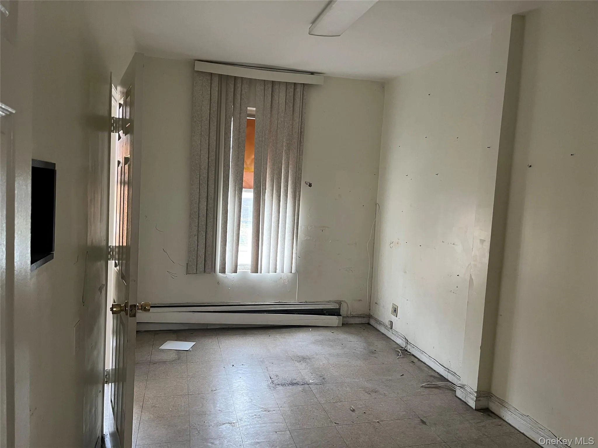 Empty room with tile patterned floors and a baseboard heating unit Empty room with tile patterned floors and a baseboard heating unit