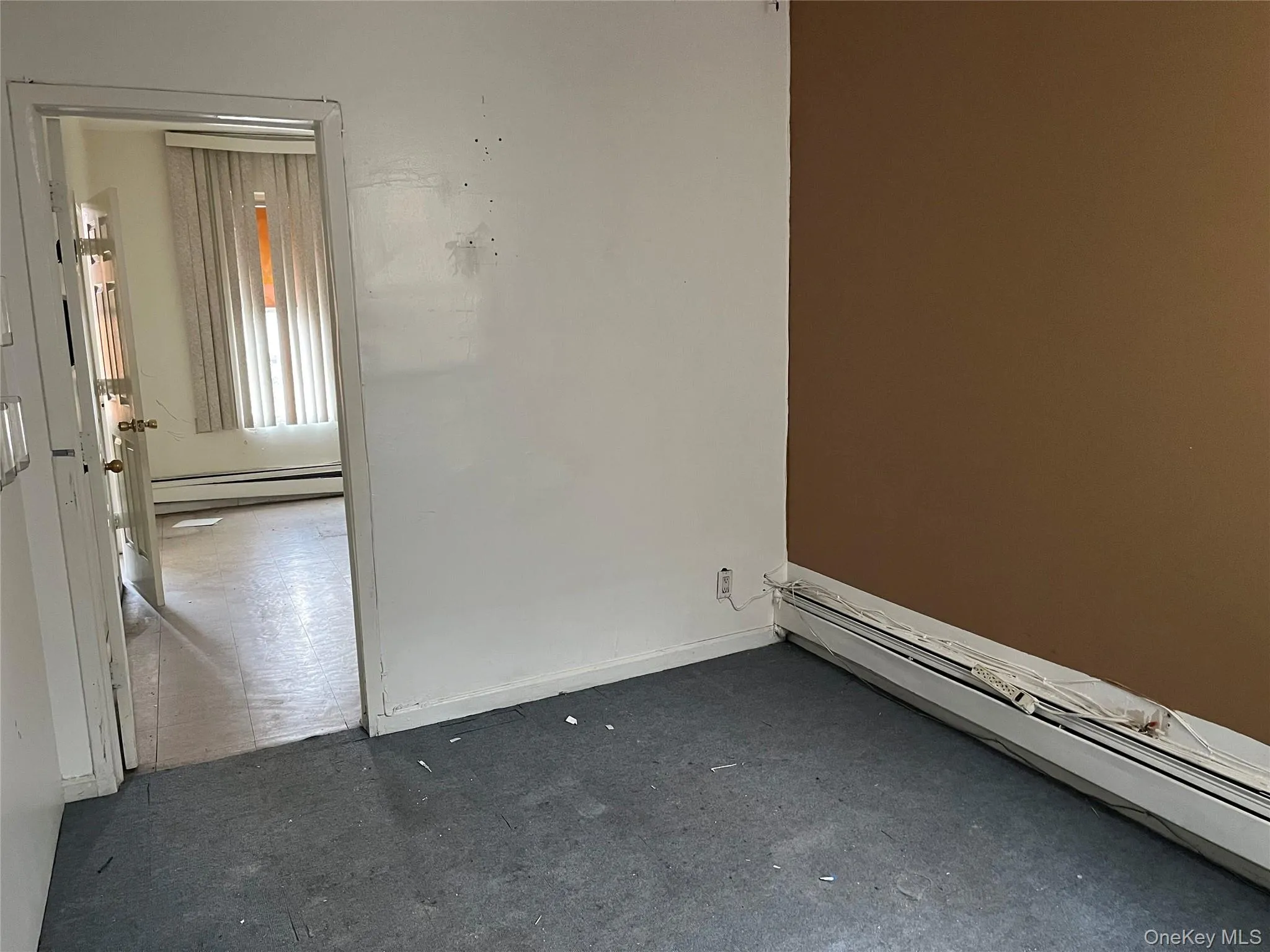 Unfurnished room featuring baseboard heating and dark colored carpet Unfurnished room featuring baseboard heating and dark colored carpet