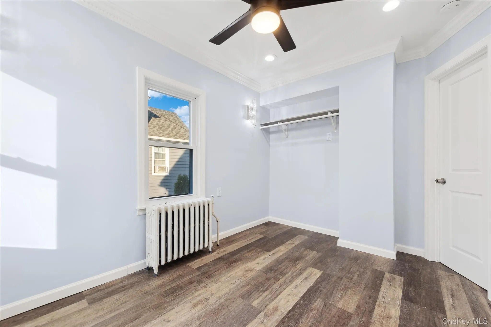 Unfurnished bedroom featuring radiator heating unit, dark wood-type flooring, ornamental molding, a ceiling fan, and recessed lighting Unfurnished bedroom featuring radiator heating unit, dark wood-type flooring, ornamental molding, a ceiling fan, and recessed lighting