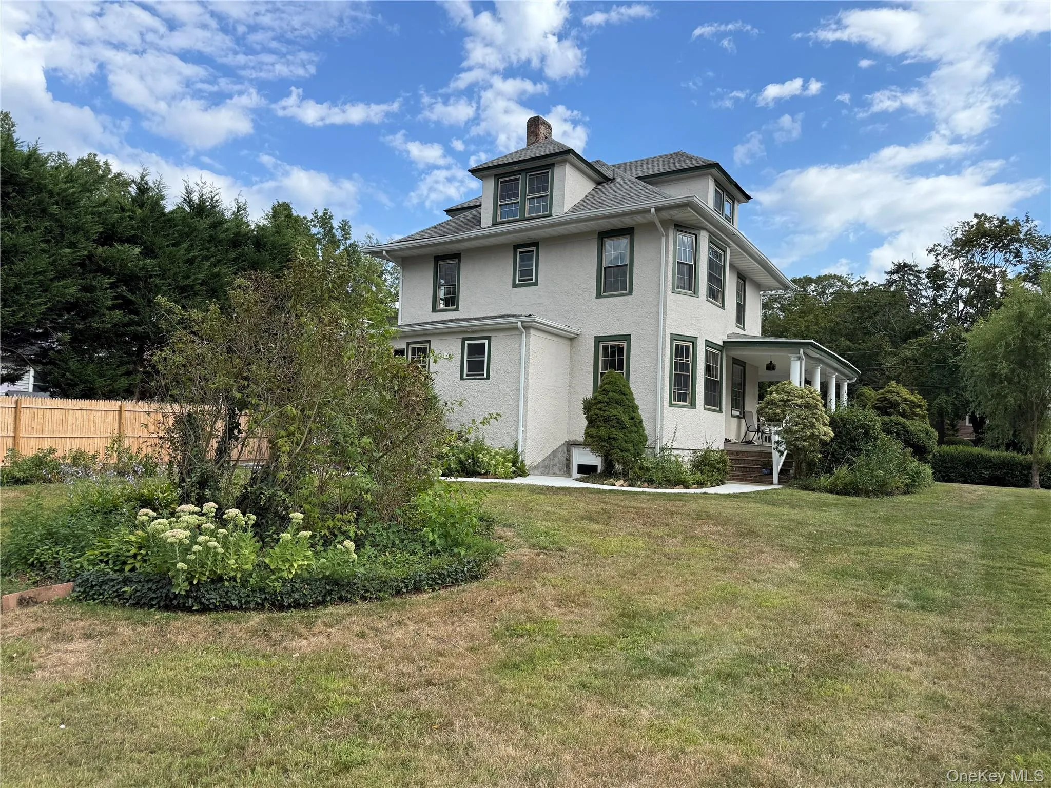 Rear view of property with a chimney, covered porch, and stucco siding Rear view of property with a chimney, covered porch, and stucco siding
