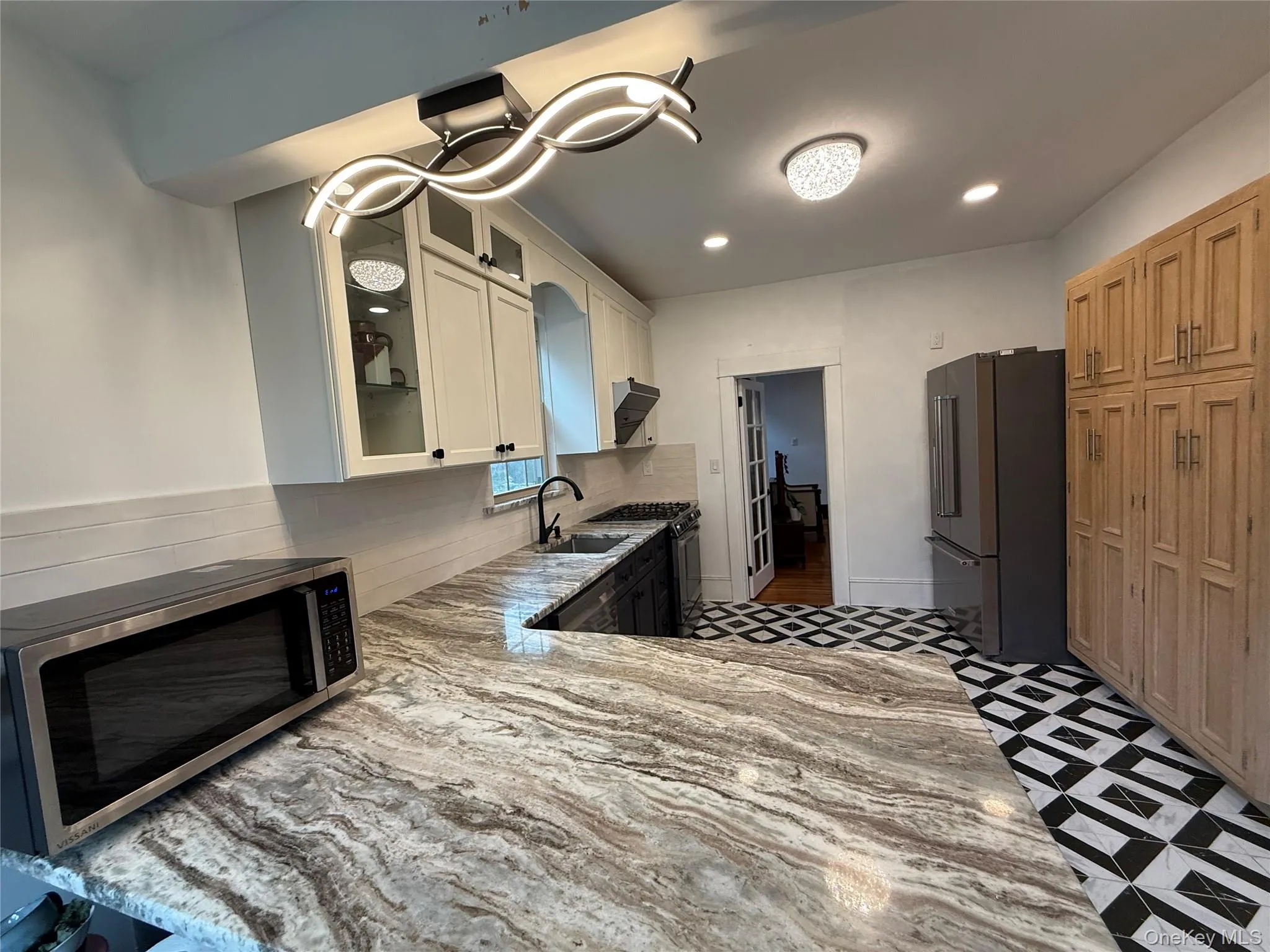 Kitchen featuring appliances with stainless steel finishes, glass insert cabinets, light stone counters, recessed lighting, and white cabinetry Kitchen featuring appliances with stainless steel finishes, glass insert cabinets, light stone counters, recessed lighting, and white cabinetry