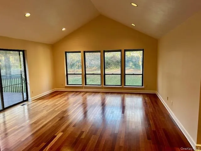 Spare room with hardwood / wood-style flooring, healthy amount of natural light, vaulted ceiling, and recessed lighting Spare room with hardwood / wood-style flooring, healthy amount of natural light, vaulted ceiling, and recessed lighting