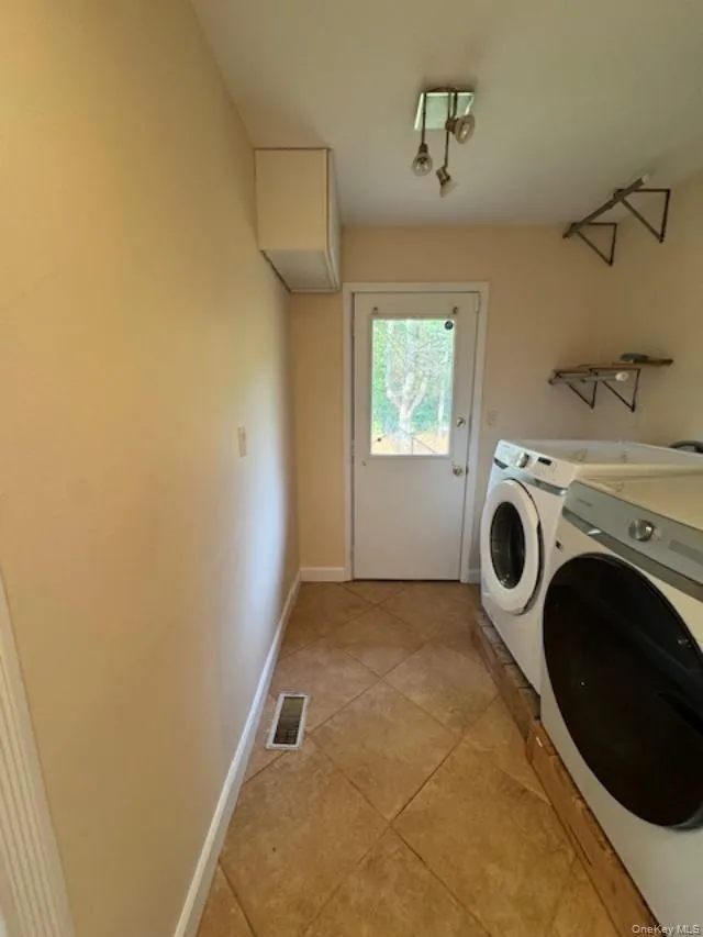 Washroom featuring washer and clothes dryer and light tile patterned floors Washroom featuring washer and clothes dryer and light tile patterned floors