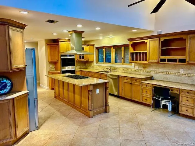 Kitchen featuring brown cabinets, light stone countertops, recessed lighting, stainless steel appliances, and light tile patterned flooring Kitchen featuring brown cabinets, light stone countertops, recessed lighting, stainless steel appliances, and light tile patterned flooring