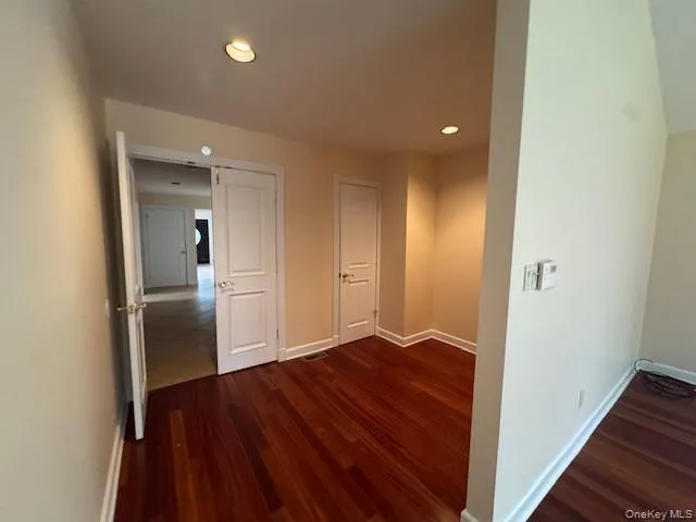 Corridor featuring dark wood-style flooring and recessed lighting Corridor featuring dark wood-style flooring and recessed lighting