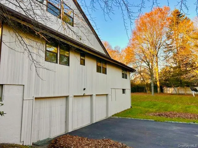 View of side of property featuring a three car garage, yard and asphalt driveway View of side of property featuring a three car garage, yard and asphalt driveway