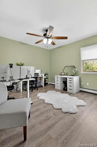 Office featuring light wood finished floors, a baseboard heating unit, and a ceiling fan Office featuring light wood finished floors, a baseboard heating unit, and a ceiling fan