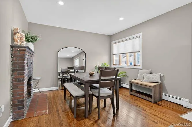 Dining space with baseboard heating, a brick fireplace, wood finished floors, recessed lighting, and a baseboard heating unit Dining space with baseboard heating, a brick fireplace, wood finished floors, recessed lighting, and a baseboard heating unit