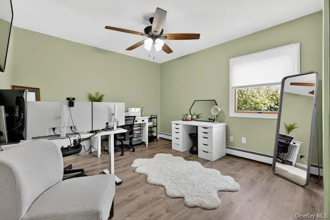 Office featuring light wood-style flooring, a ceiling fan, and a baseboard heating unit Office featuring light wood-style flooring, a ceiling fan, and a baseboard heating unit