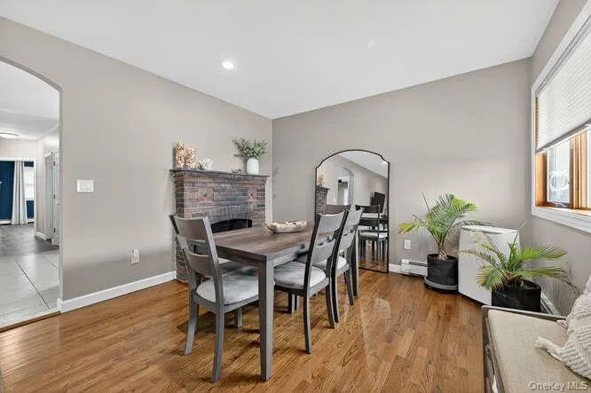 Dining room featuring arched walkways, plenty of natural light, wood finished floors, and a baseboard radiator Dining room featuring arched walkways, plenty of natural light, wood finished floors, and a baseboard radiator