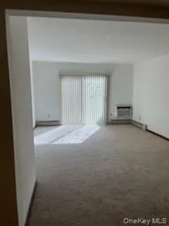 Unfurnished living room featuring carpet floors and a baseboard radiator Unfurnished living room featuring carpet floors and a baseboard radiator