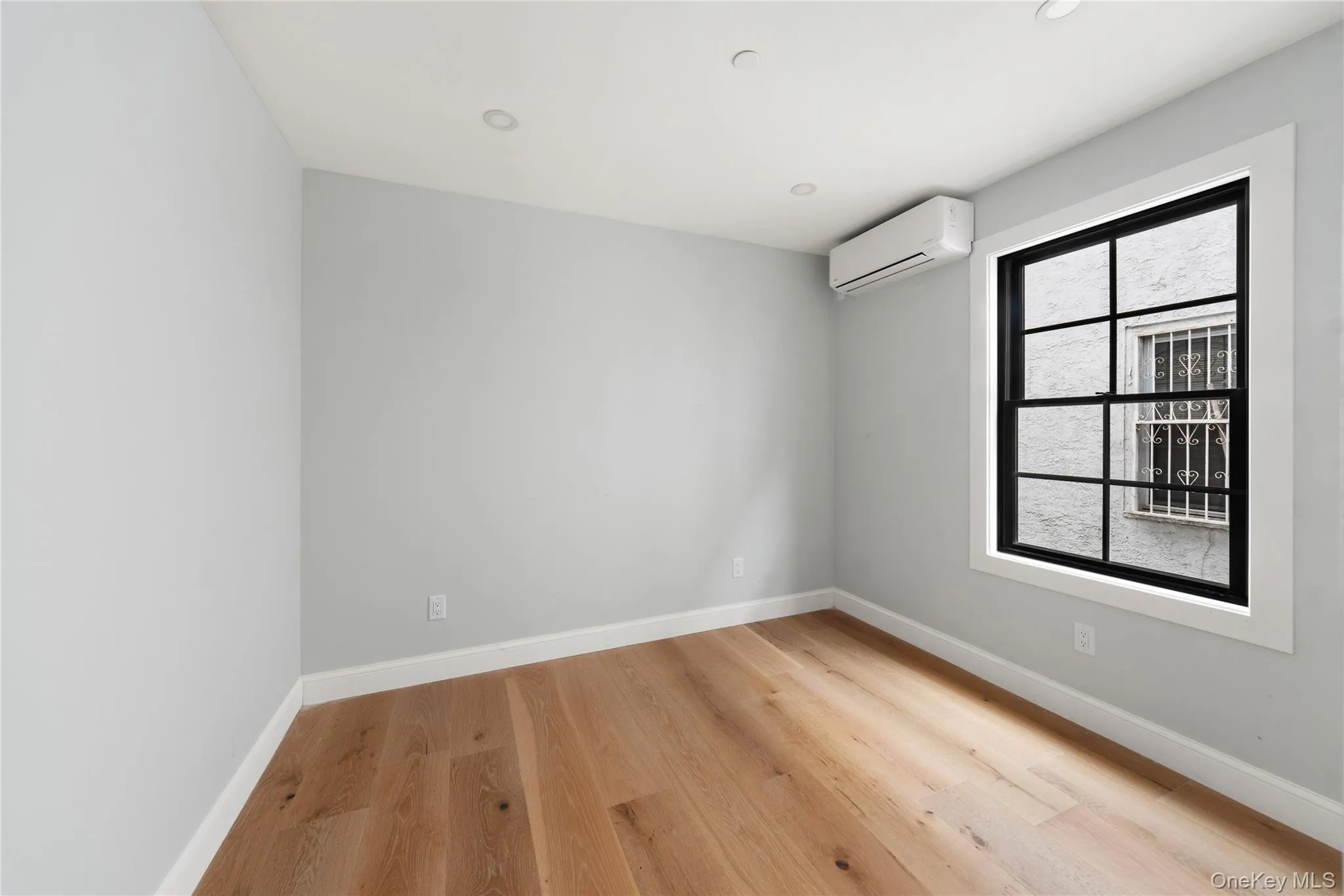 Empty room featuring light wood finished floors, recessed lighting, and a wall mounted AC Empty room featuring light wood finished floors, recessed lighting, and a wall mounted AC