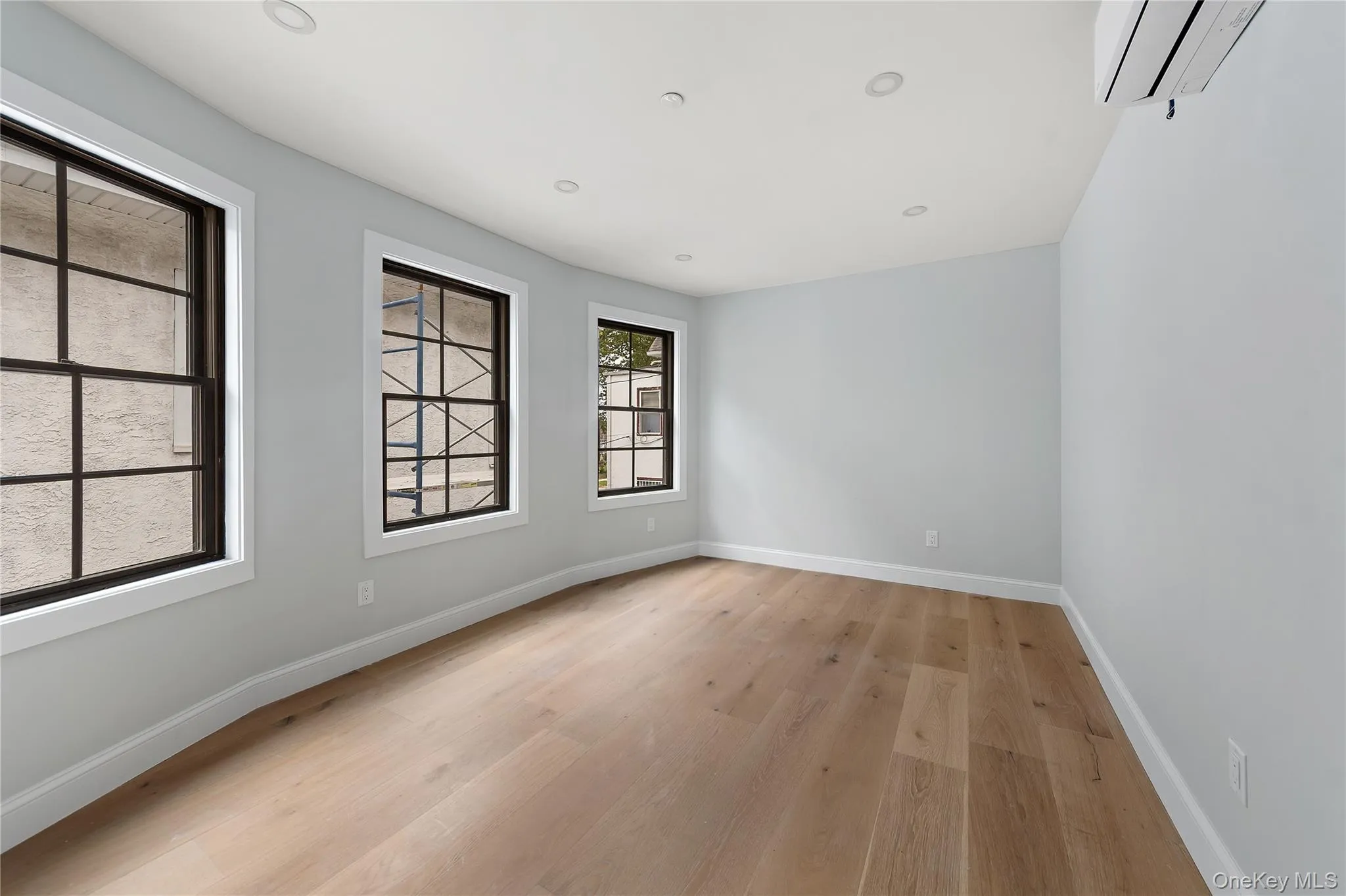 Unfurnished room with light wood-style flooring, a wall mounted AC, and recessed lighting Unfurnished room with light wood-style flooring, a wall mounted AC, and recessed lighting