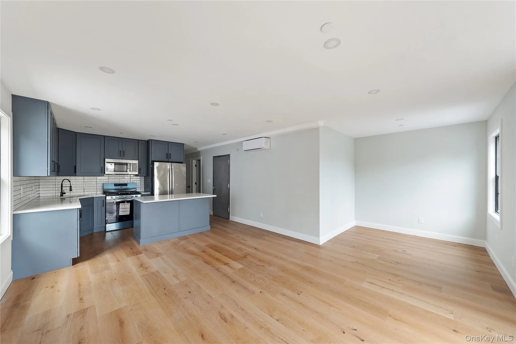 Kitchen featuring tasteful backsplash, appliances with stainless steel finishes, open floor plan, light wood-style flooring, and a center island Kitchen featuring tasteful backsplash, appliances with stainless steel finishes, open floor plan, light wood-style flooring, and a center island