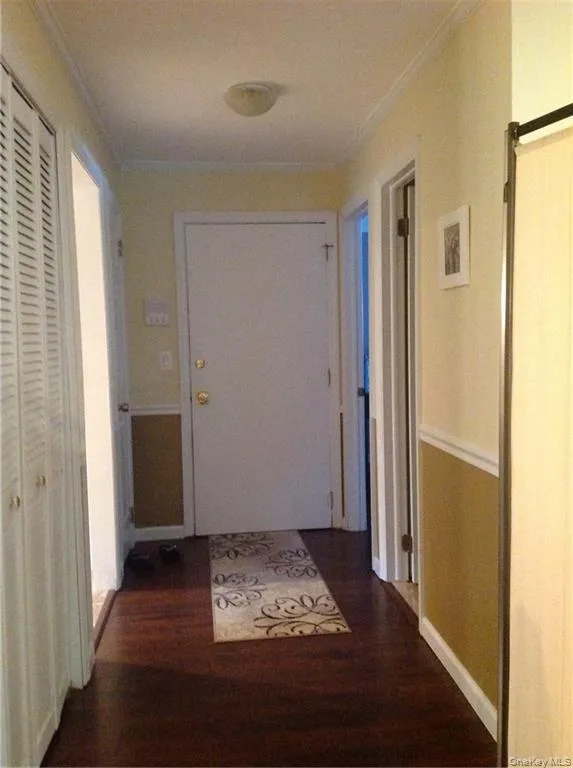 Hall featuring a barn door, crown molding, and dark wood-type flooring Hall featuring a barn door, crown molding, and dark wood-type flooring