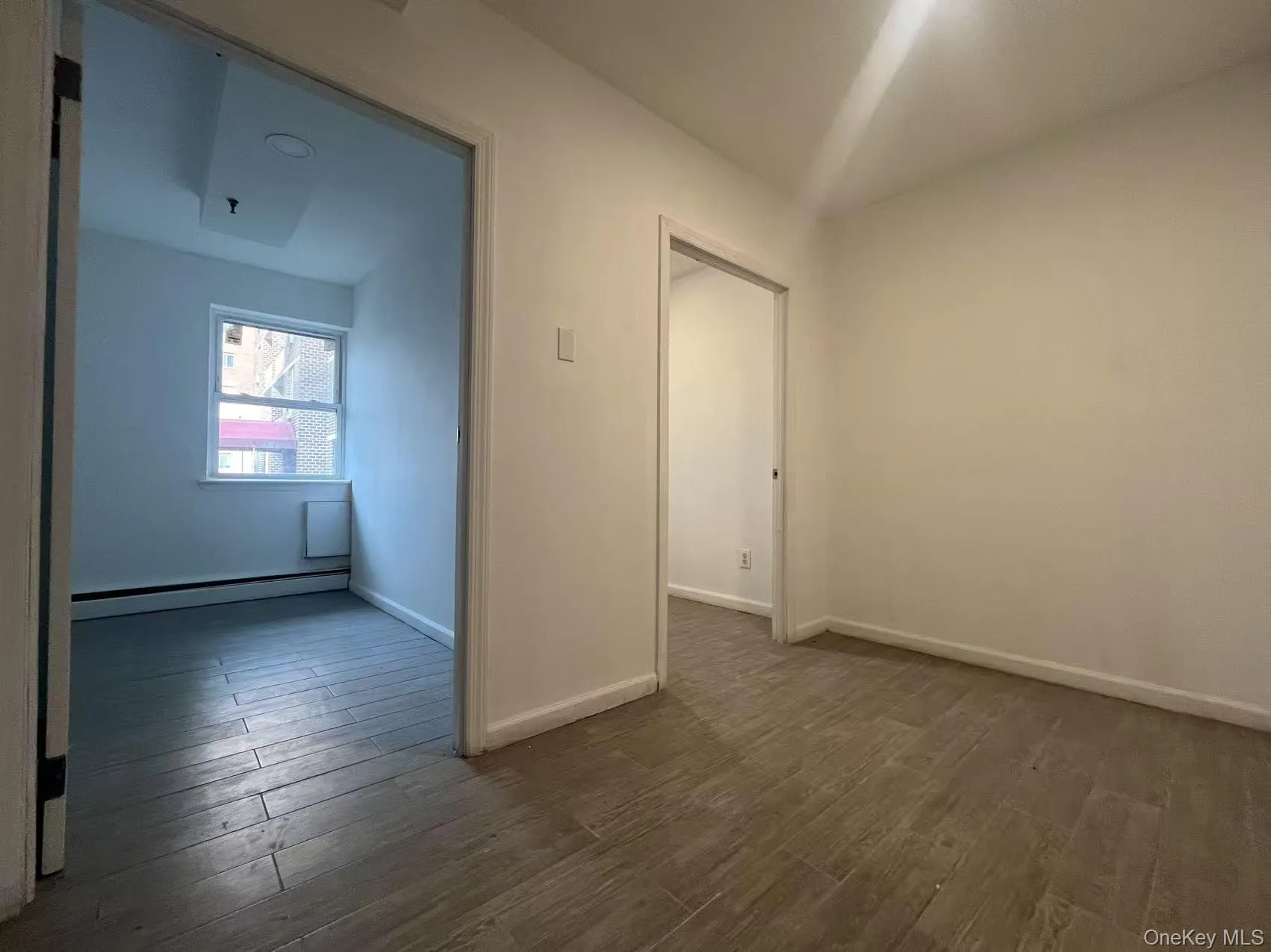 Spare room featuring dark wood-style flooring and a baseboard heating unit Spare room featuring dark wood-style flooring and a baseboard heating unit
