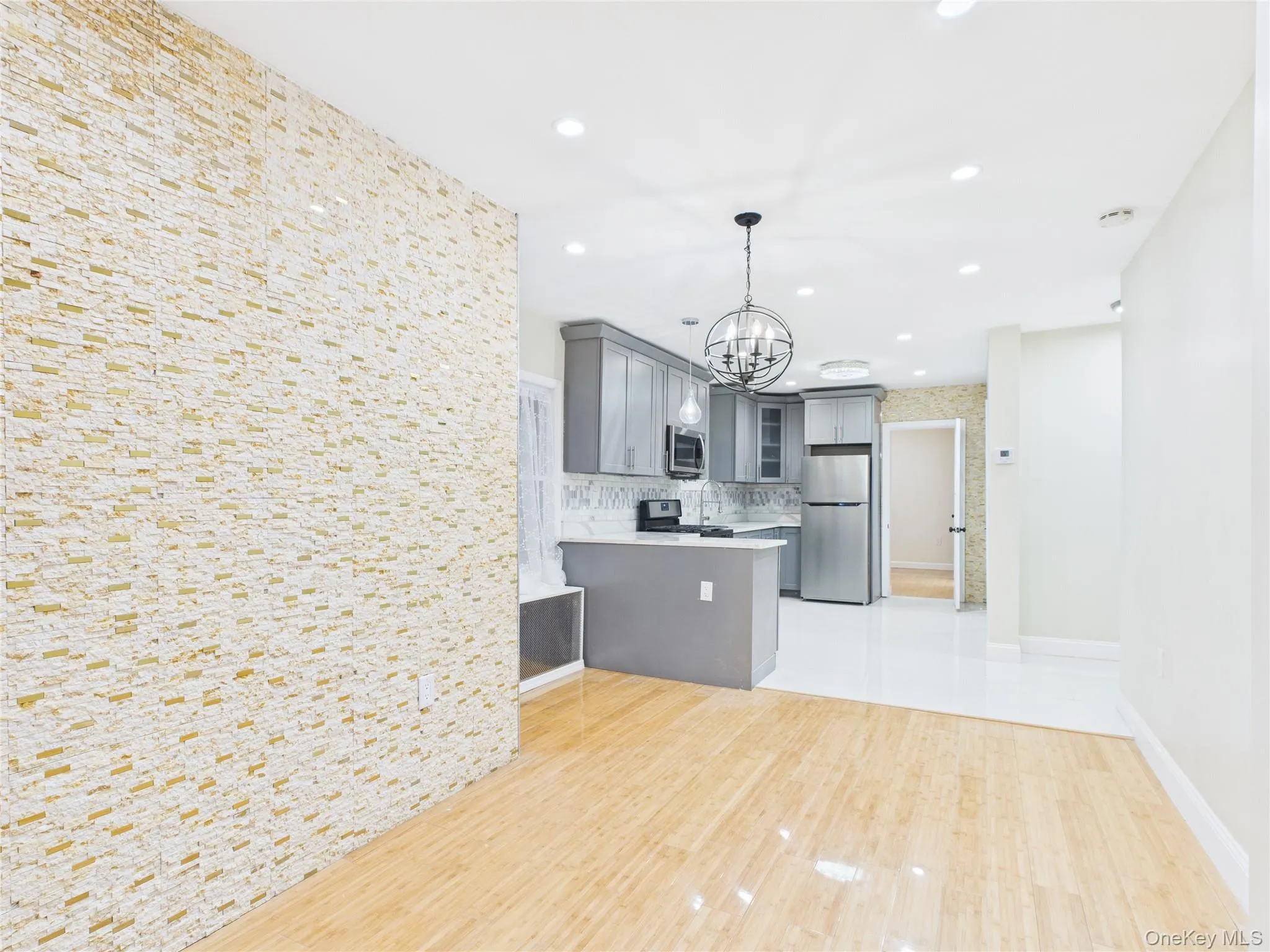 Kitchen with gray cabinetry, decorative light fixtures, a chandelier, appliances with stainless steel finishes, and a peninsula Kitchen with gray cabinetry, decorative light fixtures, a chandelier, appliances with stainless steel finishes, and a peninsula