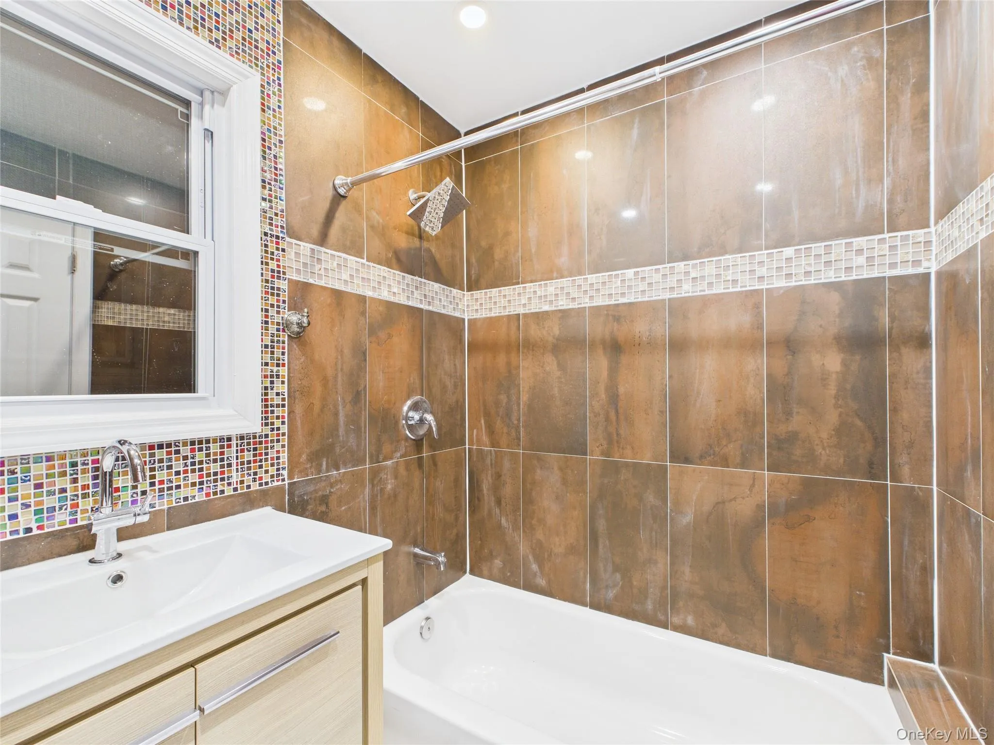 Bathroom featuring washtub / shower combination, vanity, and tile walls Bathroom featuring washtub / shower combination, vanity, and tile walls