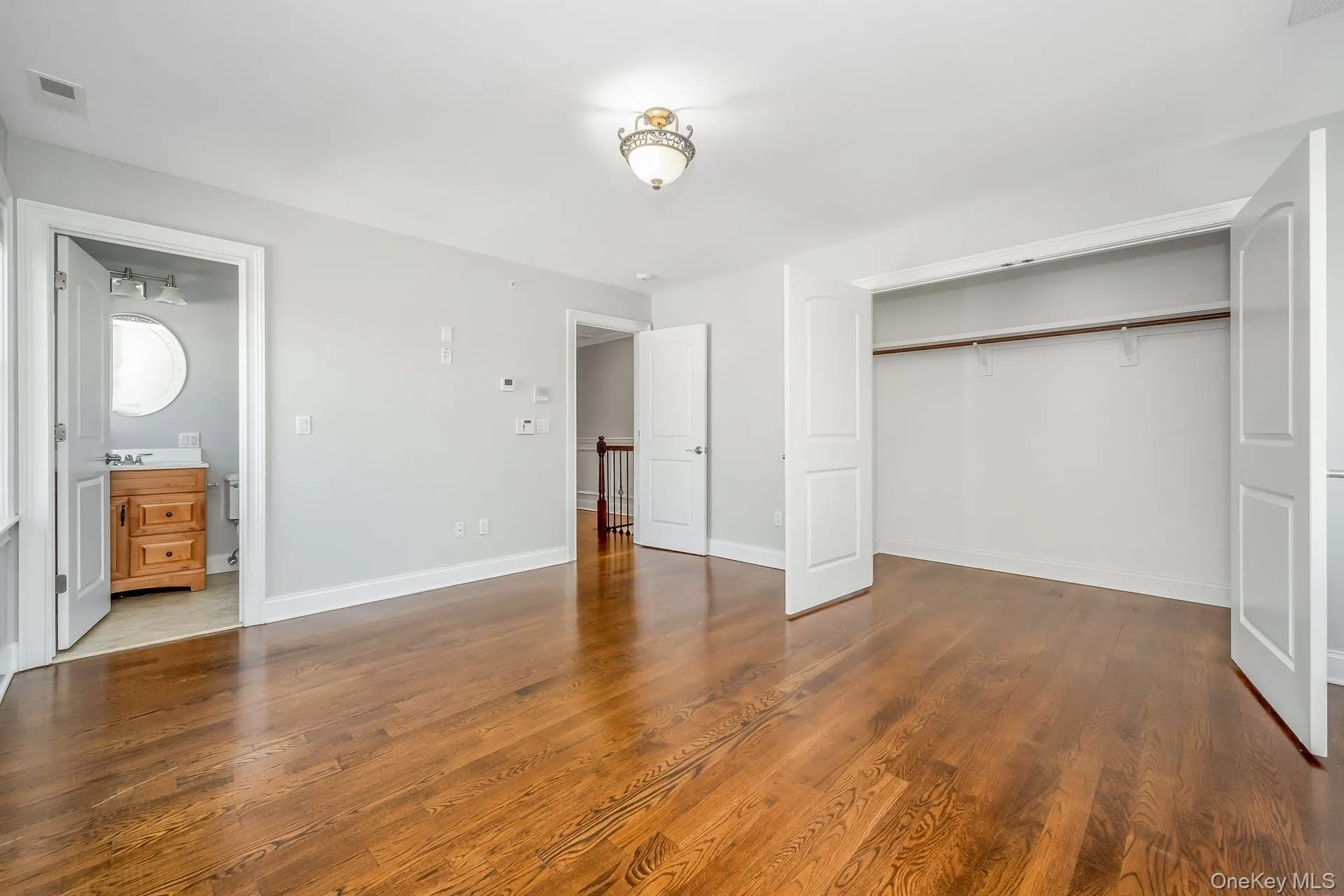 Unfurnished bedroom with dark wood-type flooring, ensuite bath, and a closet Unfurnished bedroom with dark wood-type flooring, ensuite bath, and a closet