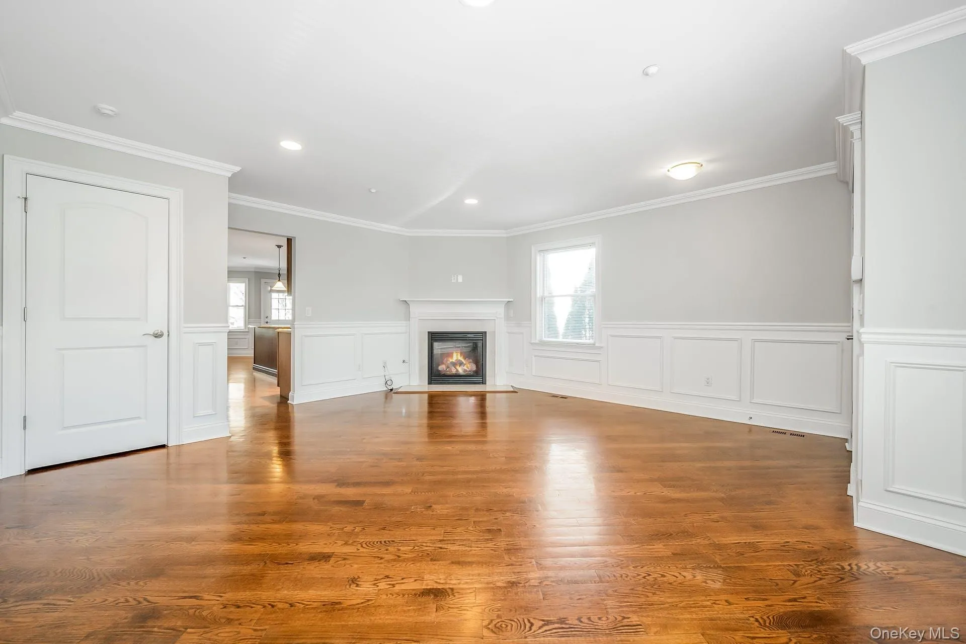 Unfurnished living room featuring plenty of natural light, a glass covered fireplace, recessed lighting, light wood-style floors, and a decorative wall Unfurnished living room featuring plenty of natural light, a glass covered fireplace, recessed lighting, light wood-style floors, and a decorative wall