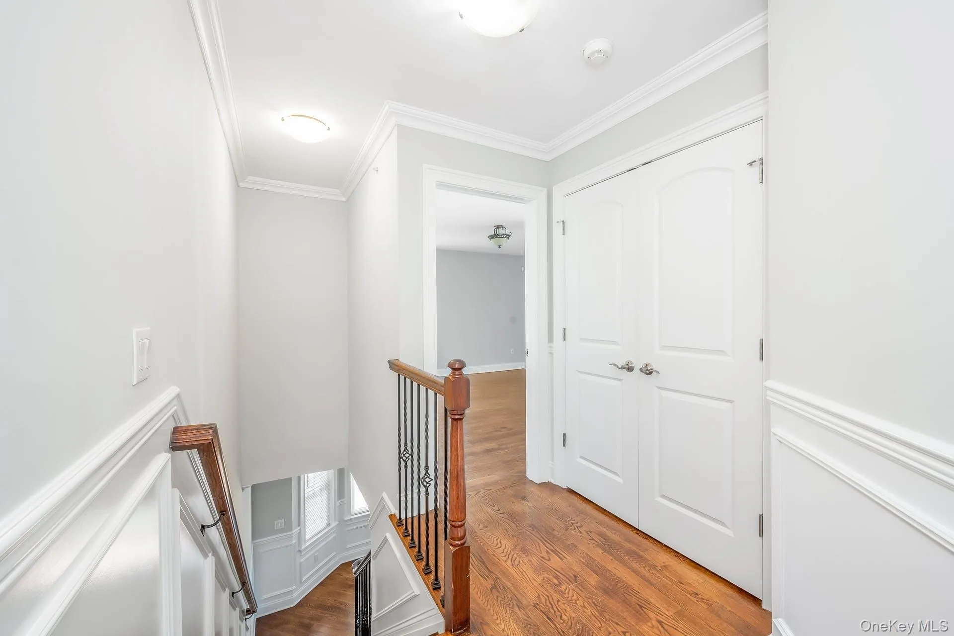 Corridor featuring an upstairs landing, wood finished floors, and ornamental molding Corridor featuring an upstairs landing, wood finished floors, and ornamental molding