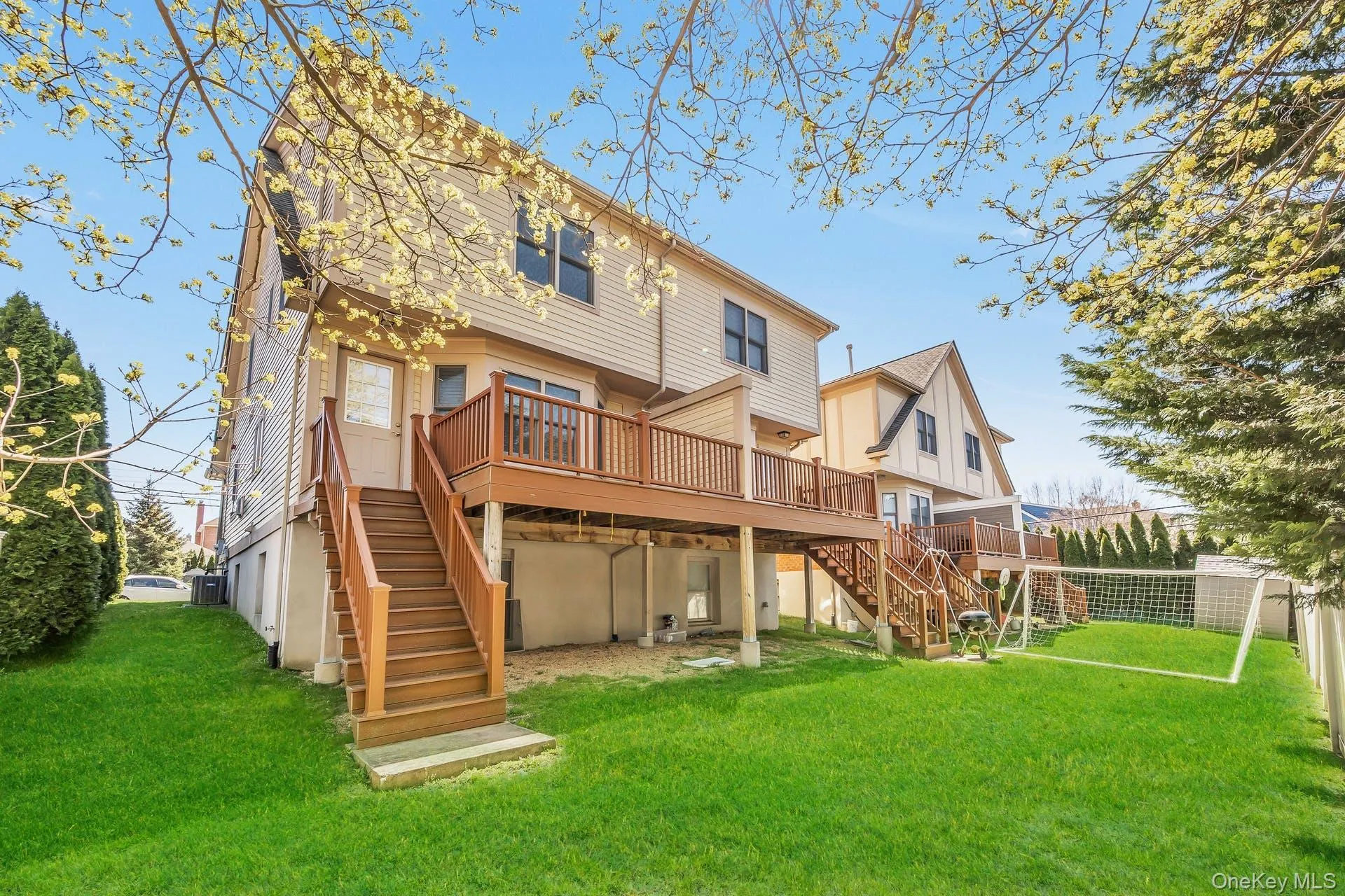 Rear view of house with stairs, a deck, and a lawn Rear view of house with stairs, a deck, and a lawn