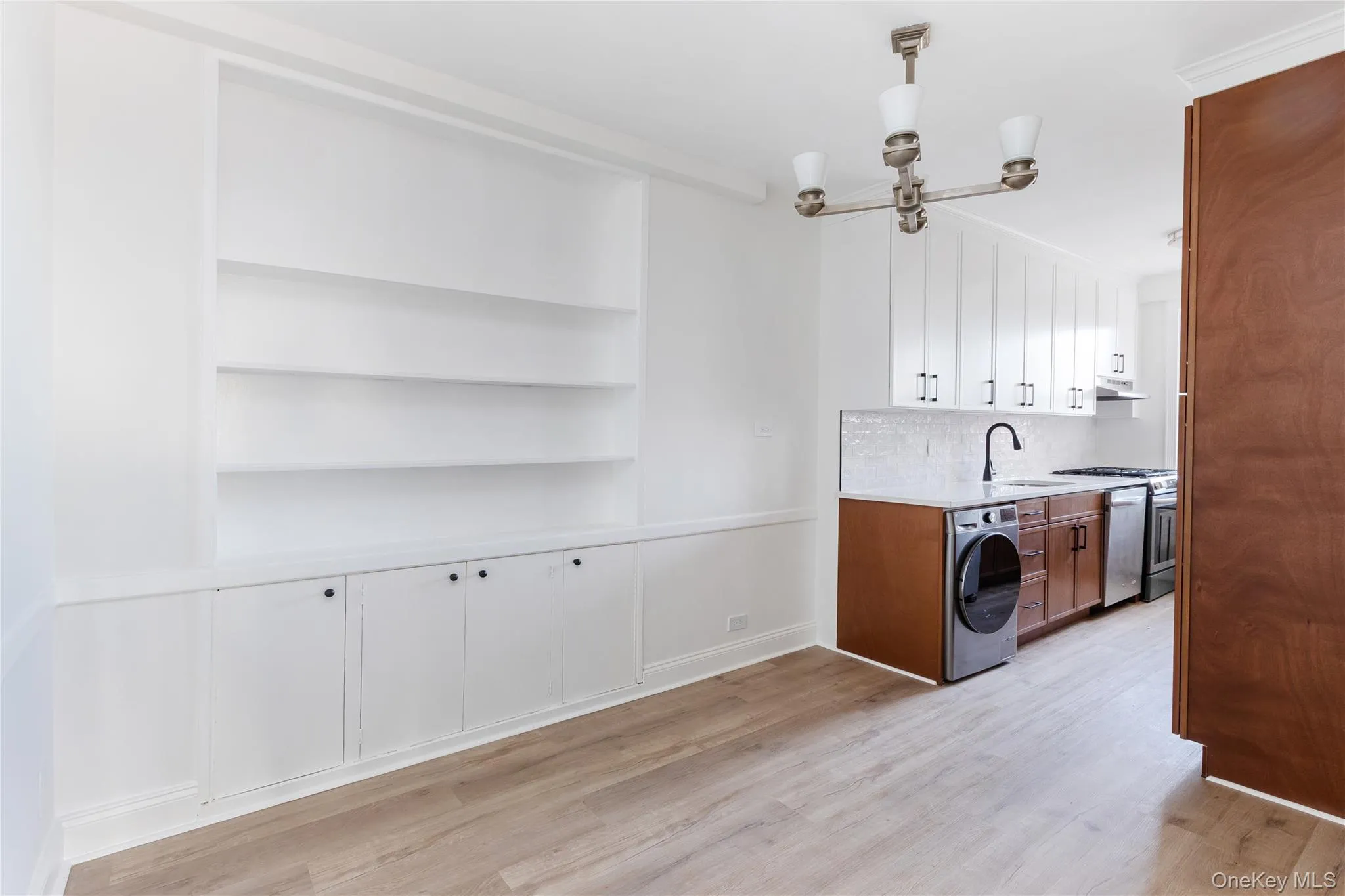 Laundry room featuring washer / dryer, a chandelier, light wood-style flooring, and built in shelves Laundry room featuring washer / dryer, a chandelier, light wood-style flooring, and built in shelves