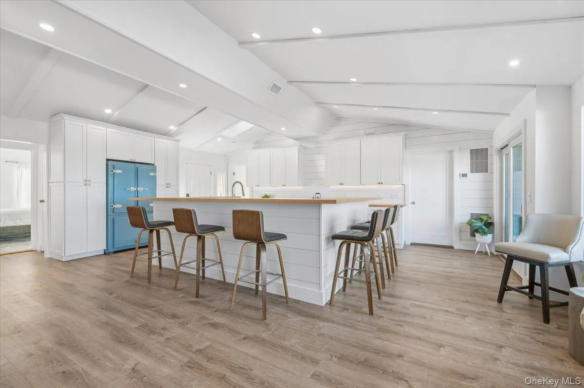 Kitchen featuring a breakfast bar, white cabinets, freestanding refrigerator, and a center island with sink Kitchen featuring a breakfast bar, white cabinets, freestanding refrigerator, and a center island with sink
