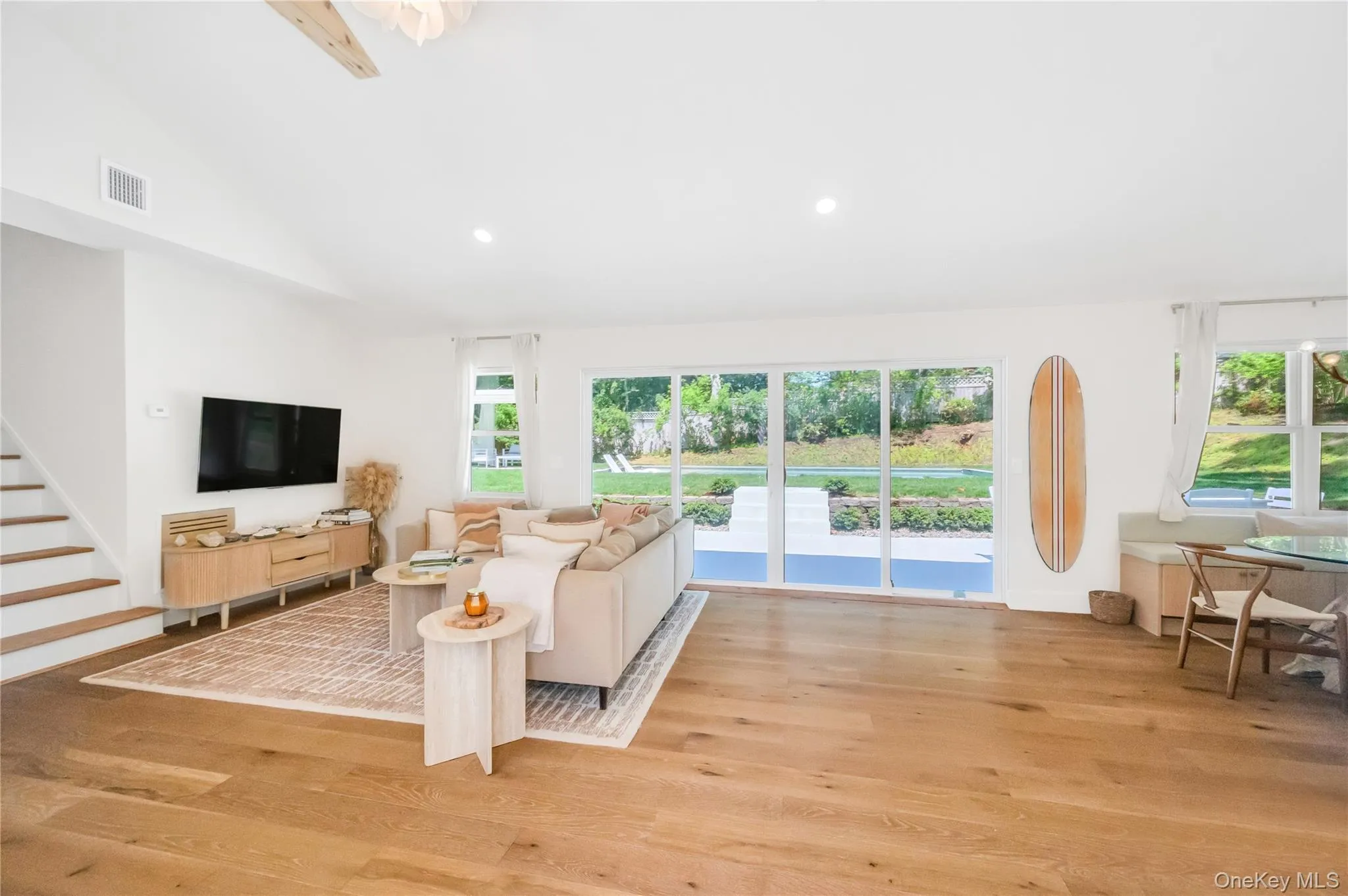 Living area featuring lofted ceiling, light wood-style flooring, stairs, and recessed lighting Living area featuring lofted ceiling, light wood-style flooring, stairs, and recessed lighting
