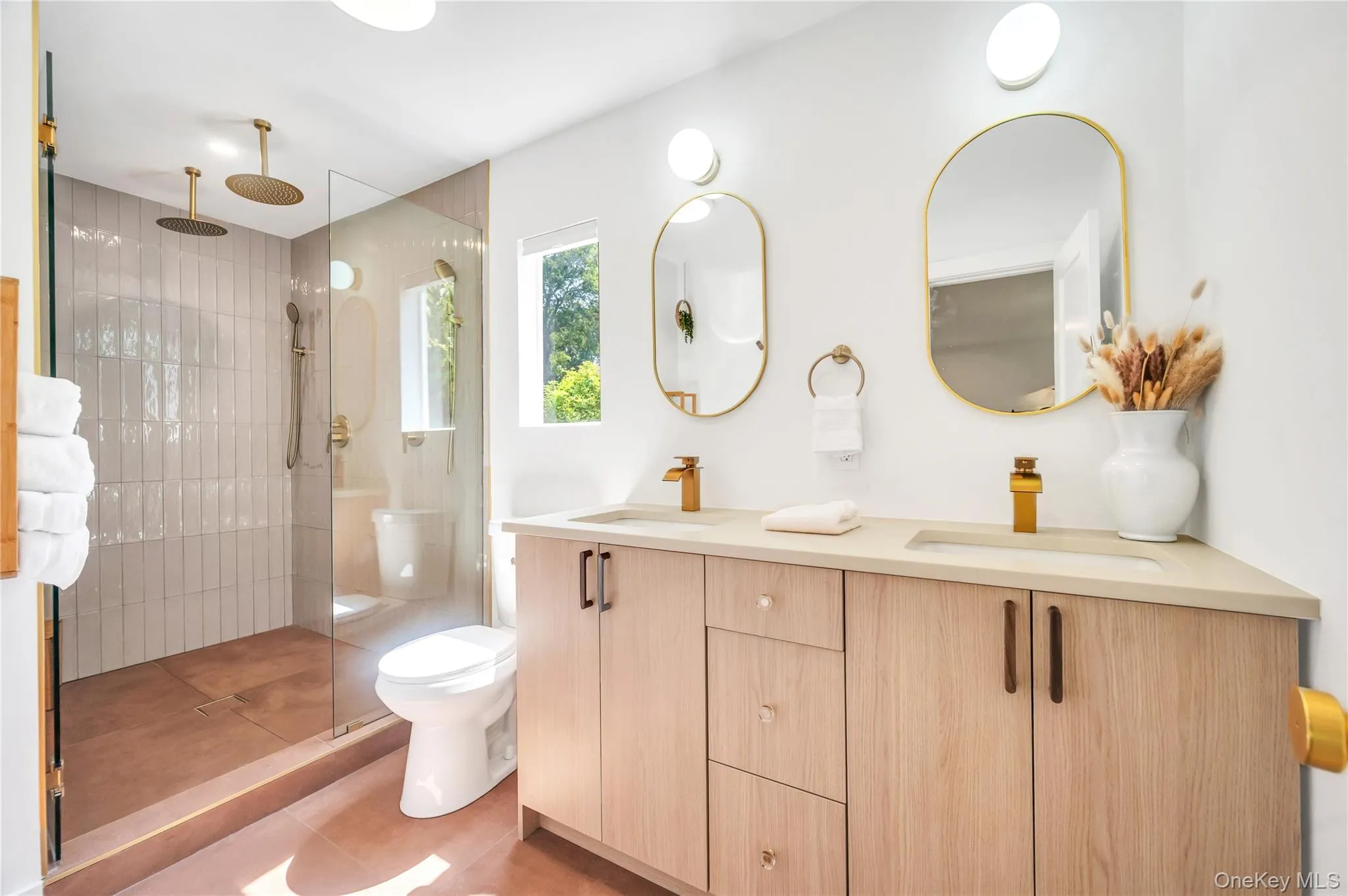 Full bathroom featuring double vanity, a tile shower, and light tile patterned floors Full bathroom featuring double vanity, a tile shower, and light tile patterned floors