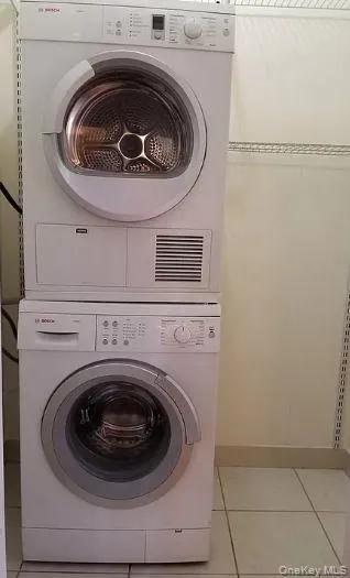 Washroom with light tile patterned floors and estacked washer and dryer Washroom with light tile patterned floors and estacked washer and dryer