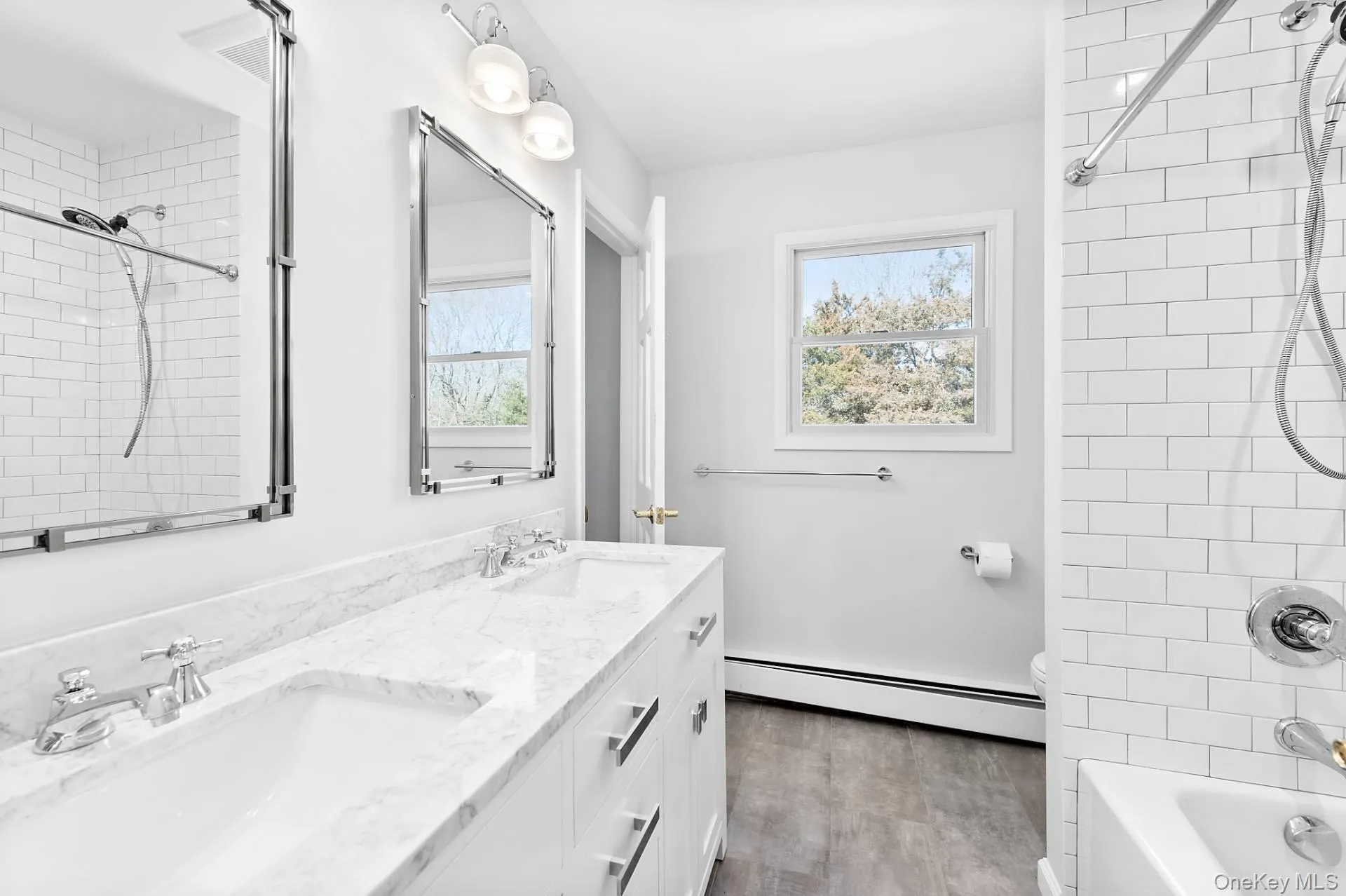Full bathroom with double vanity, a baseboard heating unit, bathing tub / shower combination, and healthy amount of natural light Full bathroom with double vanity, a baseboard heating unit, bathing tub / shower combination, and healthy amount of natural light