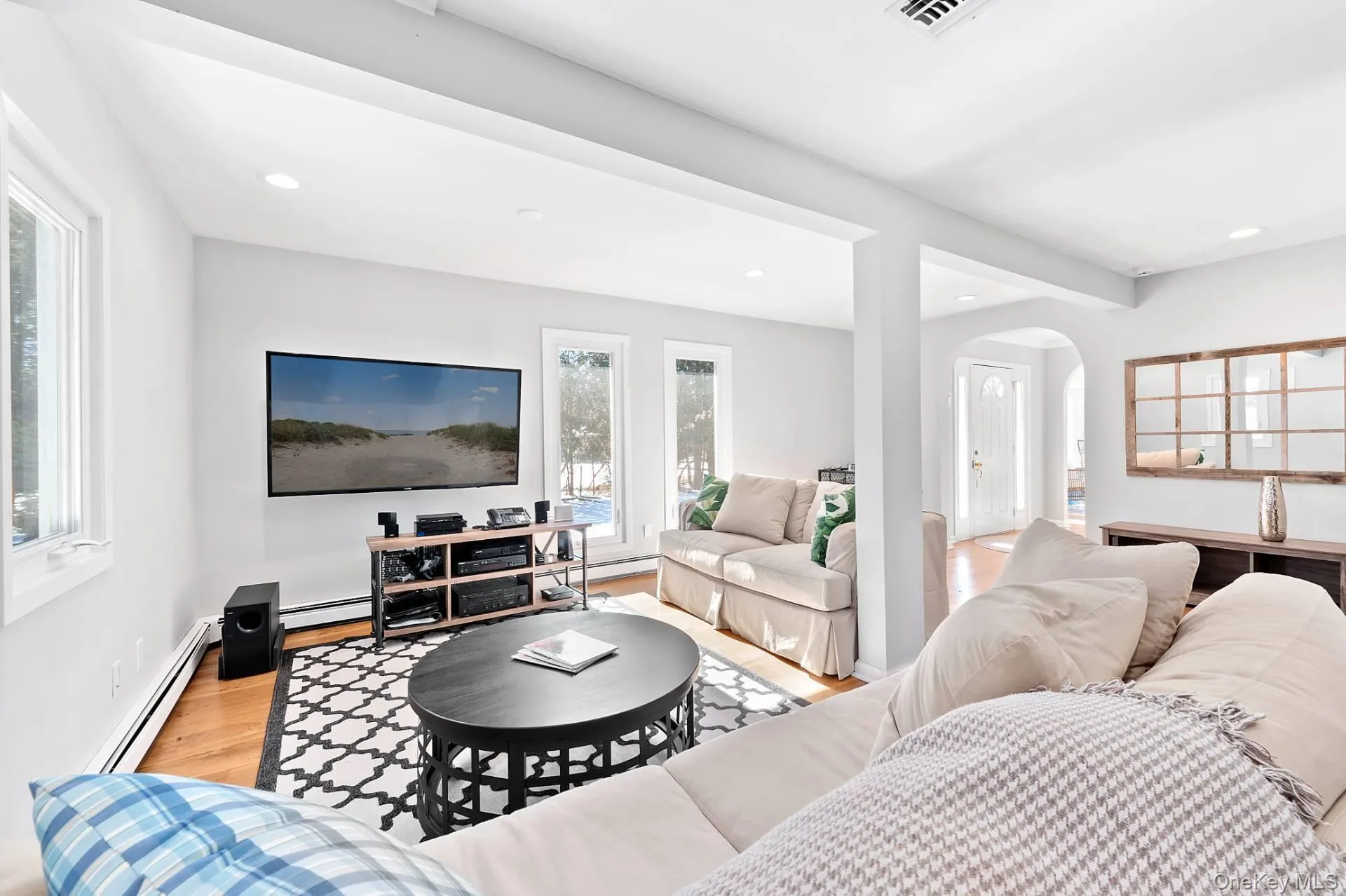 Living area with arched walkways, a baseboard radiator, light wood-type flooring, and recessed lighting Living area with arched walkways, a baseboard radiator, light wood-type flooring, and recessed lighting