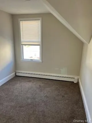 Additional living space with a baseboard heating unit, dark colored carpet, and lofted ceiling Additional living space with a baseboard heating unit, dark colored carpet, and lofted ceiling