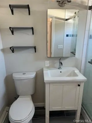 Full bathroom featuring a stall shower, vanity, a baseboard radiator, and dark tile patterned flooring Full bathroom featuring a stall shower, vanity, a baseboard radiator, and dark tile patterned flooring