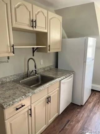 Kitchen featuring white dishwasher, dark wood-style floors, and white cabinets Kitchen featuring white dishwasher, dark wood-style floors, and white cabinets