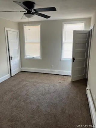 Unfurnished room featuring dark colored carpet and ceiling fan Unfurnished room featuring dark colored carpet and ceiling fan