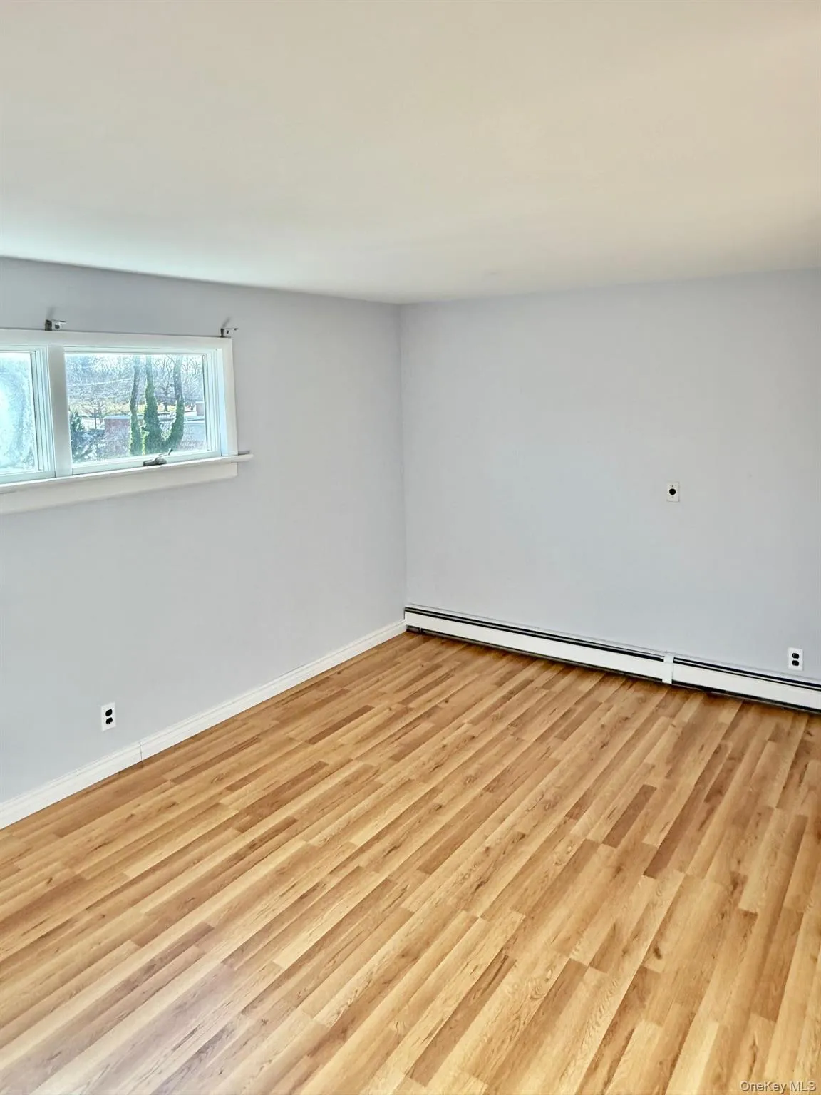 Unfurnished room featuring a baseboard heating unit and light wood finished floors Unfurnished room featuring a baseboard heating unit and light wood finished floors