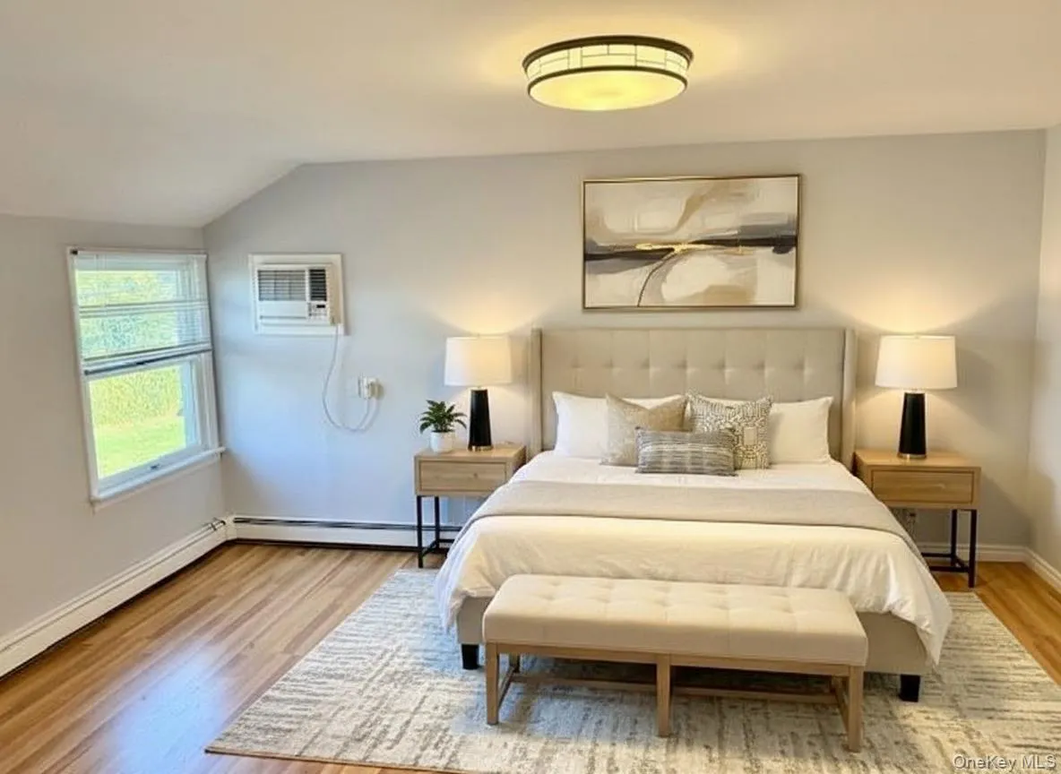 Bedroom featuring wood finished floors, lofted ceiling, a wall unit AC, and a baseboard radiator Bedroom featuring wood finished floors, lofted ceiling, a wall unit AC, and a baseboard radiator
