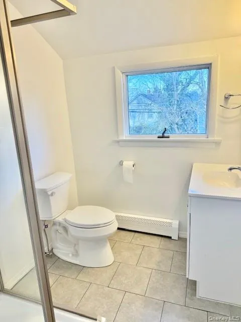 Bathroom with vanity, a shower stall, a baseboard heating unit, light tile patterned flooring, and healthy amount of natural light Bathroom with vanity, a shower stall, a baseboard heating unit, light tile patterned flooring, and healthy amount of natural light