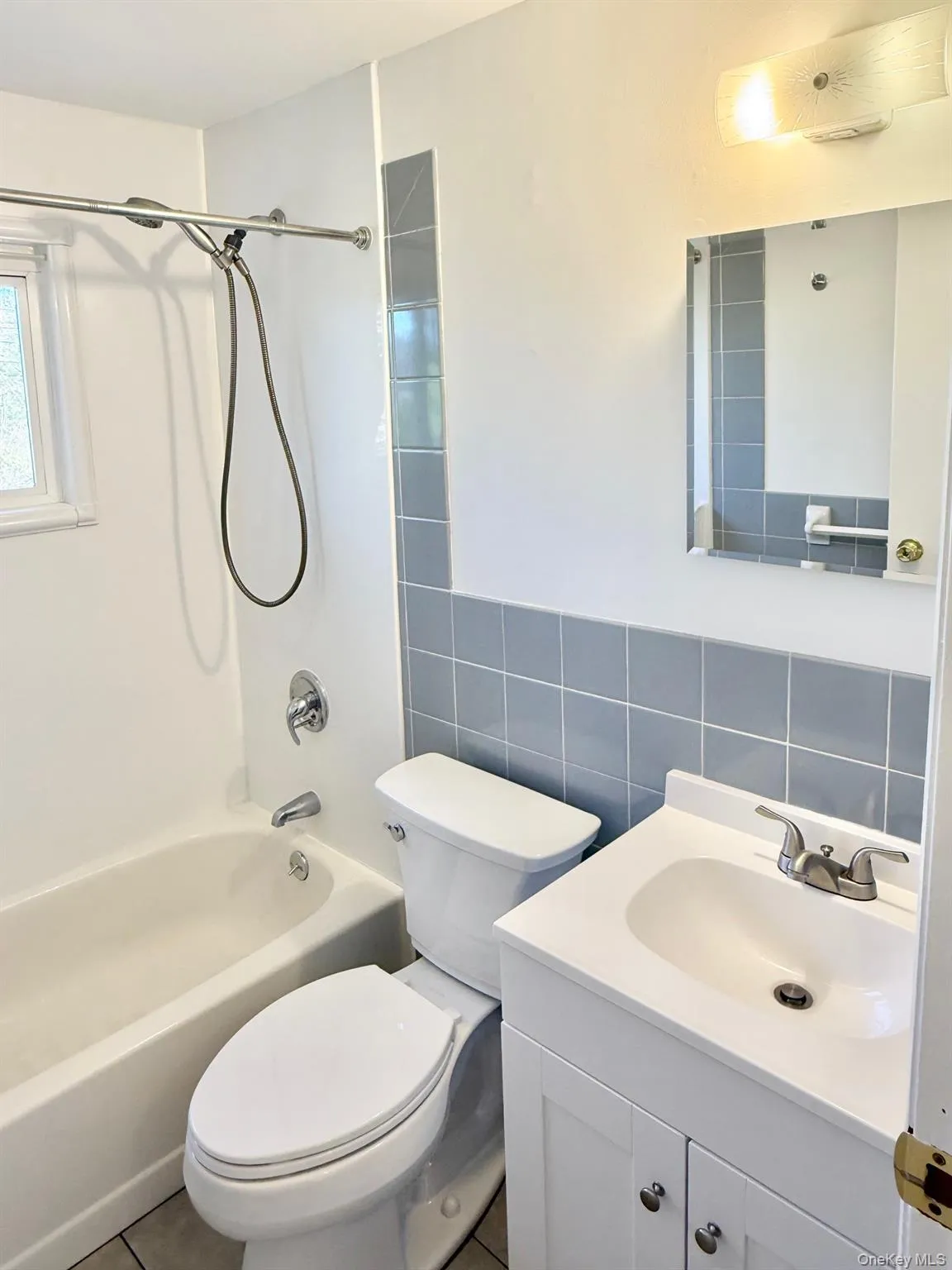 Bathroom featuring shower / washtub combination, vanity, tile walls, and tile patterned floors Bathroom featuring shower / washtub combination, vanity, tile walls, and tile patterned floors