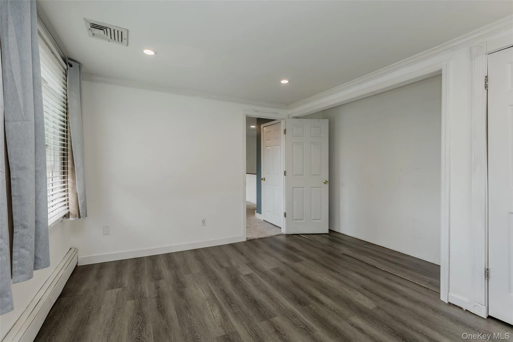 Unfurnished bedroom featuring a baseboard heating unit, recessed lighting, wood finished floors, and crown molding Unfurnished bedroom featuring a baseboard heating unit, recessed lighting, wood finished floors, and crown molding