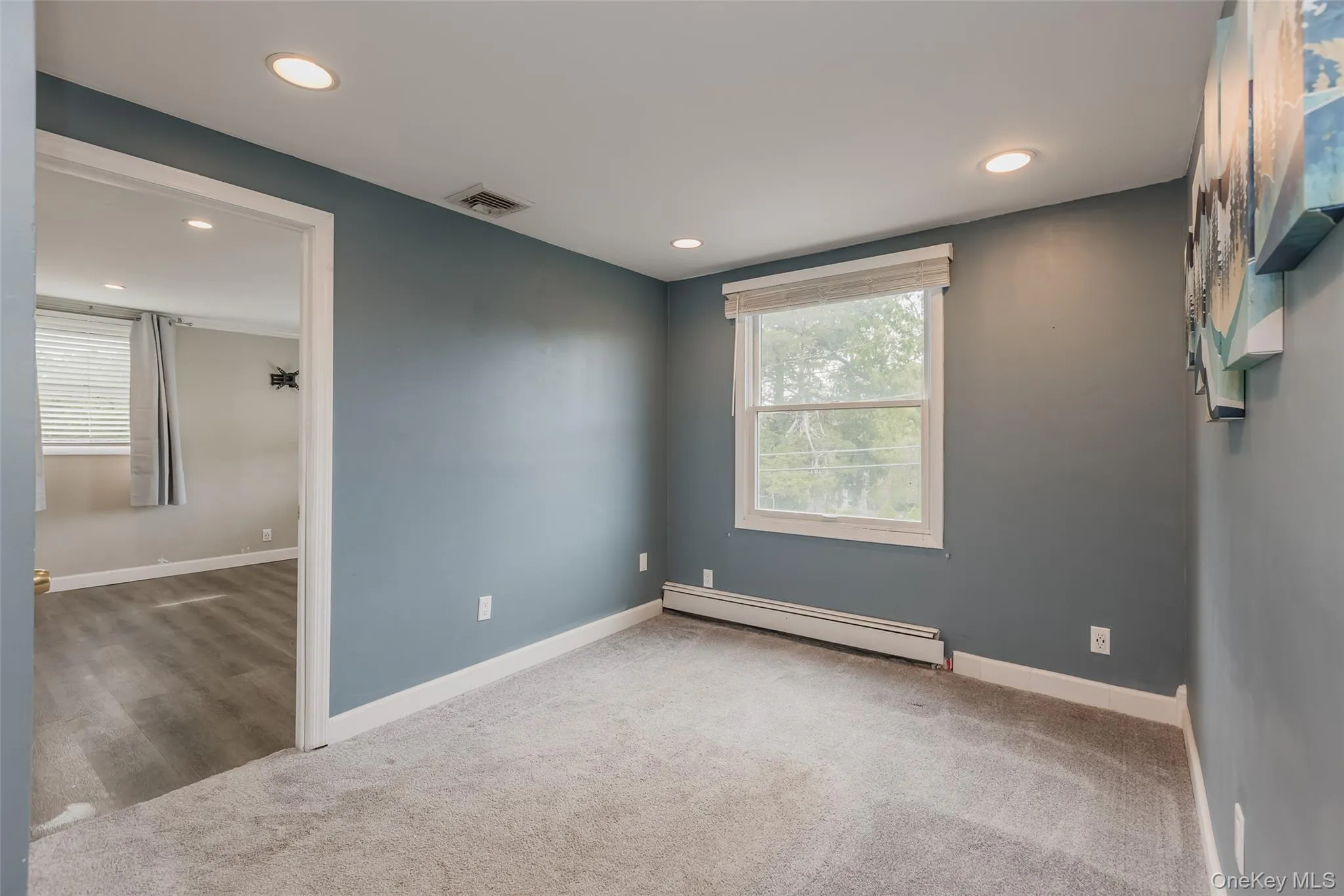 Spare room with baseboard heating, recessed lighting, plenty of natural light, and light carpet Spare room with baseboard heating, recessed lighting, plenty of natural light, and light carpet