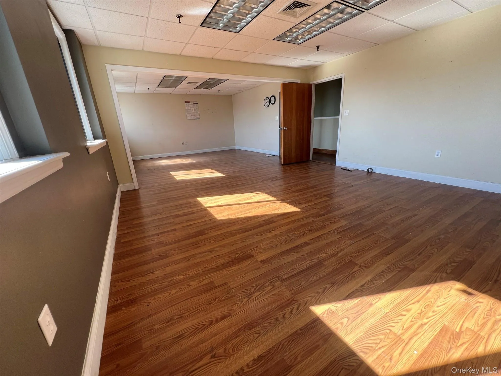 Spare room featuring wood finished floors and a paneled ceiling Spare room featuring wood finished floors and a paneled ceiling